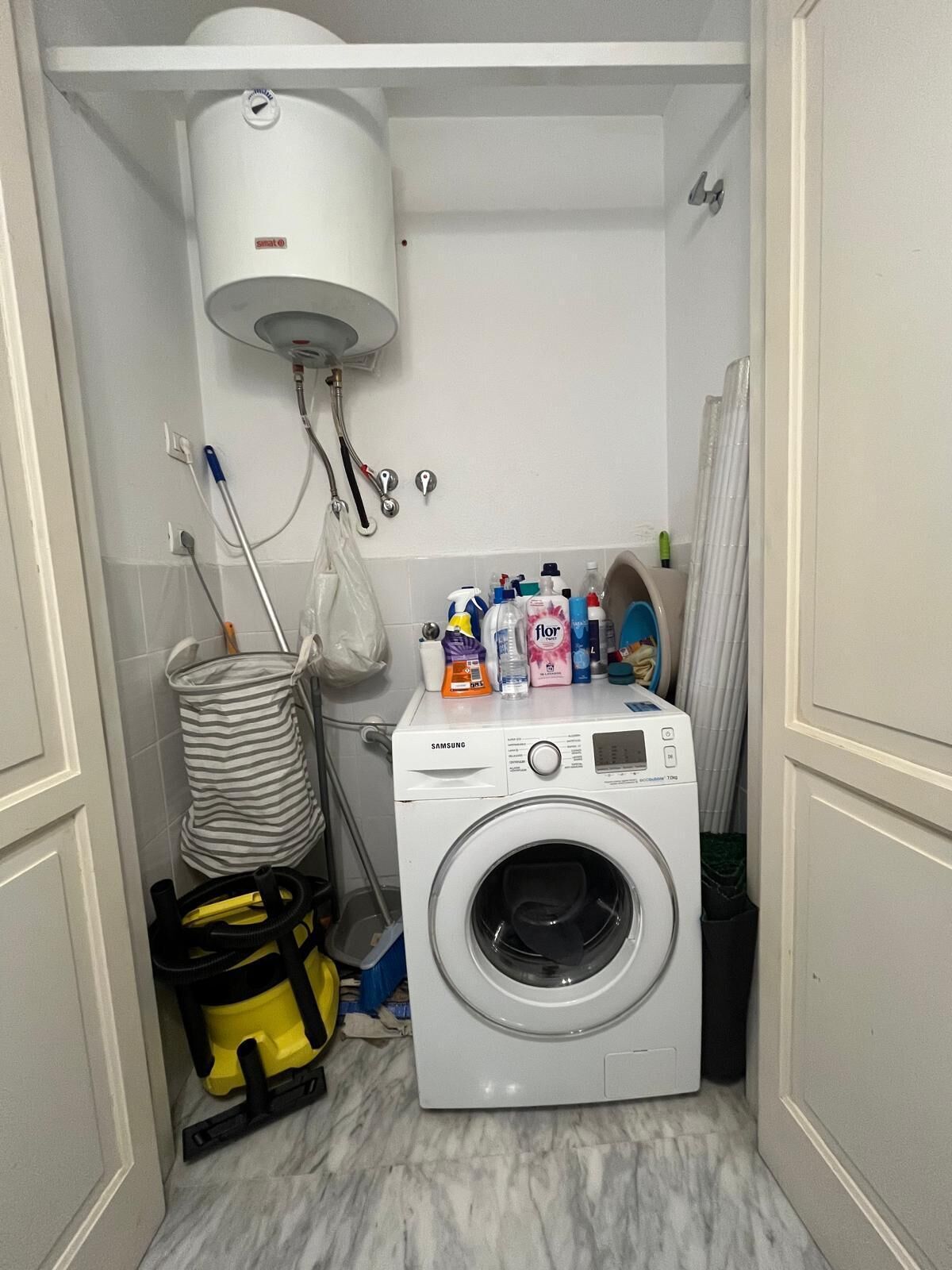 Une buanderie équipée d’un lave-linge, d’un chauffe-eau et de produits de nettoyage.
