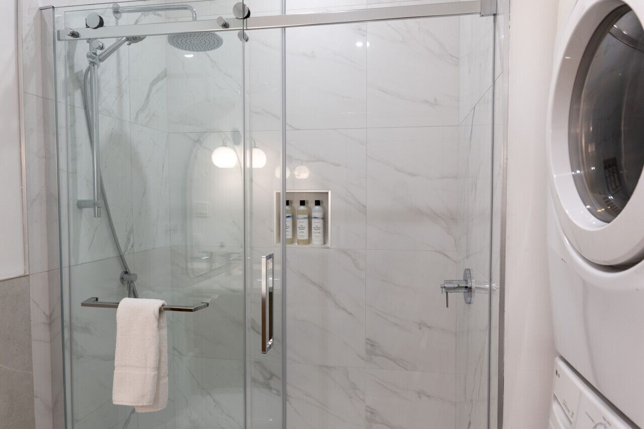 Una cabina doccia in vetro con portasci, pannello di controllo e lavatrice integrata.