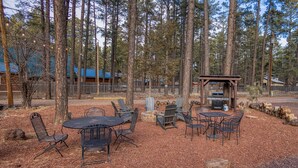 An outdoor seating area with tables and chairs, a barbecue grill, and a pergola. - Timber Lodge (Pinetop-Lakeside)