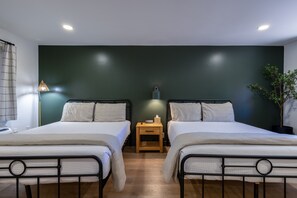 A room with two beds, a nightstand, a lamp, and a potted plant. - Timber Lodge (Pinetop-Lakeside)