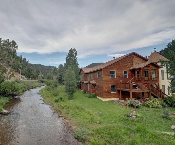 Une maison en bois avec un porche et une rivière en arrière-plan.