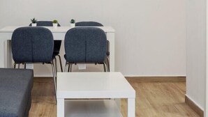 Een minimalistische kamer met een wit bureau, twee grijze stoelen, een witte tafel en een grijze bank.