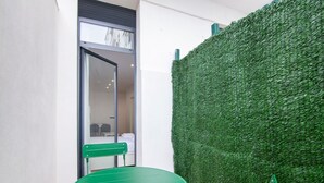 Een kamer met een groene tafel en stoelen, een glazen deur naar een andere kamer, en een muur bekleed met kunstmatig gras.