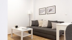 A modern living room with a grey sofa, white coffee table, and a grey armchair. There are two framed abstract artworks on the wall. - VLC HOST - Fray Pedro B (Valencia)