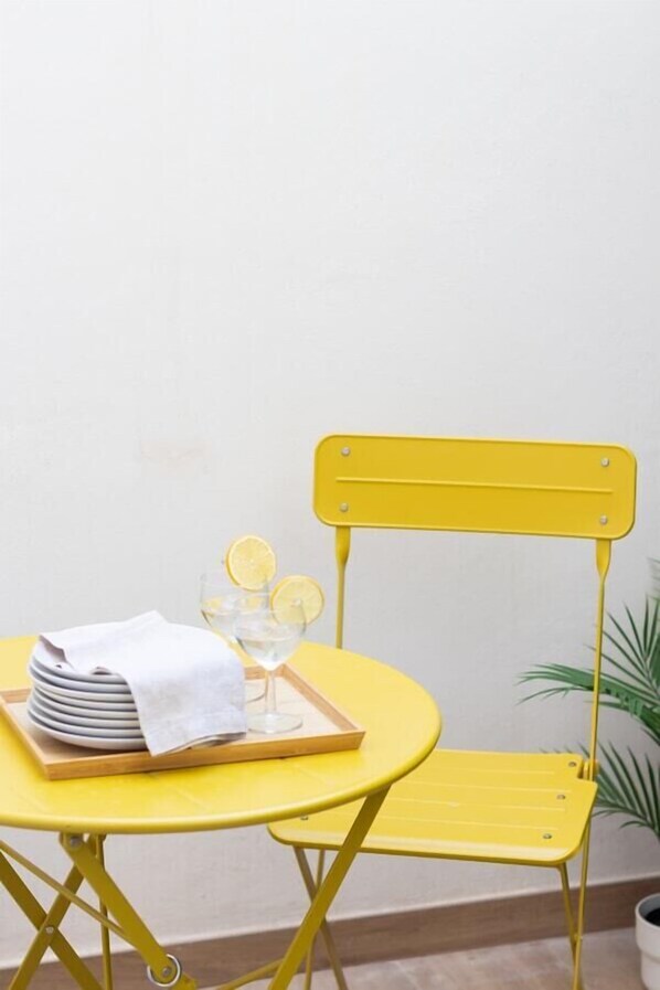 A yellow metal chair and table with a tray holding plates and a glass. - VLC HOST - Fray Pedro B (Valencia)