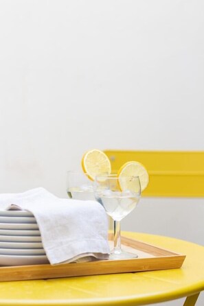 A yellow chair with a tray holding a glass of water and lemon slices, a white cloth, and a stack of plates. - VLC HOST - Fray Pedro B (Valencia)
