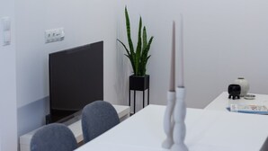 A modern, minimalist room with a white table, a black TV stand, a potted plant, and a decorative vase. - VLC HOST - Fray Pedro B (Valencia)
