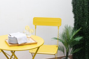 A yellow table with a tray of plates and glasses, a white towel, and a yellow chair. - VLC HOST - Fray Pedro B (Valencia)