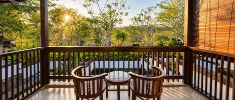 A wooden deck with a table and chairs, surrounded by a railing, overlooking a lush garden.