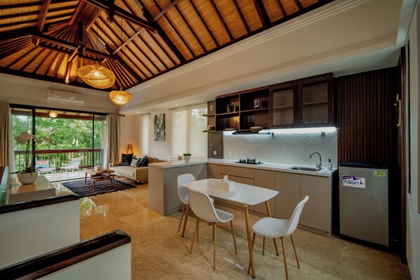 A modern kitchen with a dining area, large windows, and a ceiling with exposed beams. - Avana Villa Jimbaran By Fays Hospitality (Jimbaran)