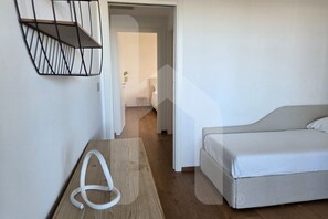 A bedroom with a bed, a wooden table, and a white cable. - WaterFront is an exclusive and refined complex in one of the most suggestive stretches of the Montesilvano seafront and a few steps from the large golden sandy beaches. The Interno 7 apartment, on the ground floor of the residence also reachable by eleva (Montesilvano)