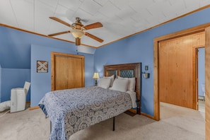 A bedroom with a bed, a ceiling fan, a wooden wardrobe, and a wall-mounted lamp. - Downtown Lincoln Basecamp! (Lincoln)