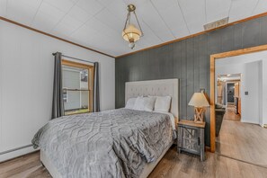 A bedroom with a large bed, a bedside lamp, and a view of the hallway. - Downtown Lincoln Basecamp! (Lincoln)