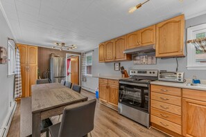 A kitchen with wooden cabinets, a stainless steel refrigerator, a stove, and a toaster. - Downtown Lincoln Basecamp! (Lincoln)