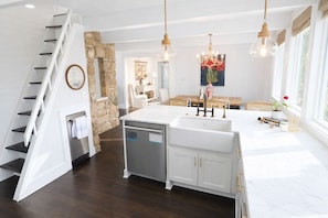Una cocina moderna con una isla central, armarios blancos y una pared de acento de piedra.