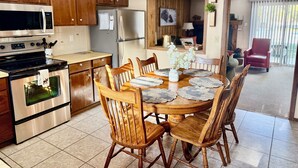 Una cocina moderna con armarios de madera, electrodomésticos de acero inoxidable y un comedor con mesa y sillas de madera.