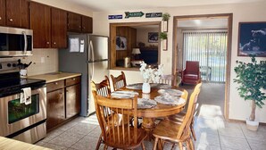 Una cocina con armarios de madera, electrodomésticos de acero inoxidable y un comedor con mesa y sillas de madera.