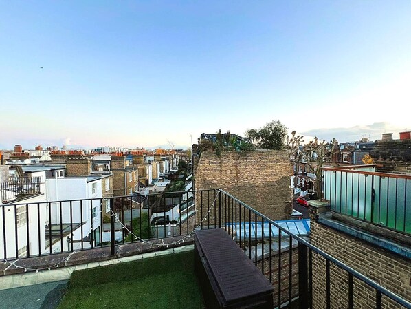 A residential area with a brick wall, a small grassy area, and a metal railing.