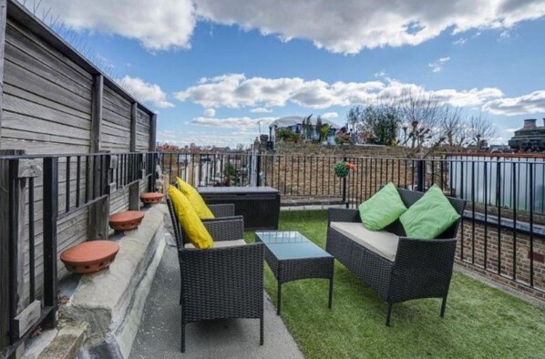 An outdoor patio with wicker furniture, a small table, and terracotta planters.