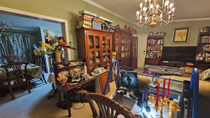 A cozy living room with a dining area, a chandelier, and a bookshelf. - 3-bedroom house in delightful S Raleigh WiFi, AC (Raleigh)