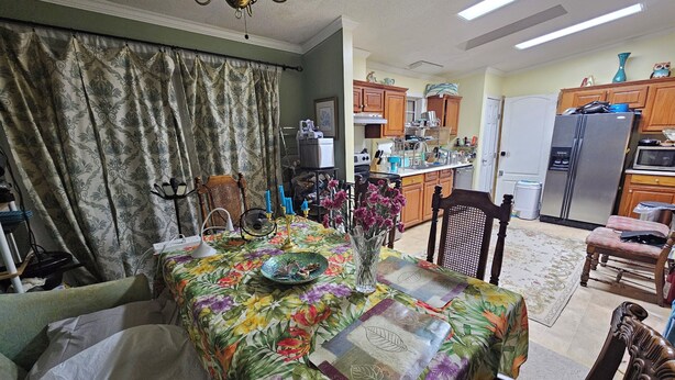 A dining area with a floral tablecloth, a chandelier, and a view into the kitchen with wooden cabinets and appliances. - 3-bedroom house in delightful S Raleigh WiFi, AC (Raleigh)
