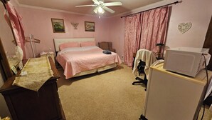 A bedroom with a bed, a desk, a chair, a ceiling fan, and a microwave. - 3-bedroom house in delightful S Raleigh WiFi, AC (Raleigh)