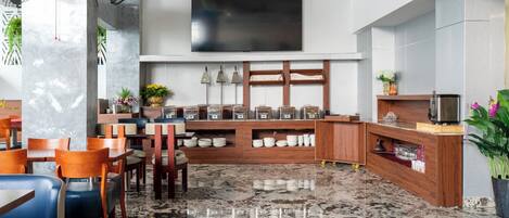 Un espace repas moderne avec un sol en marbre, des meubles en bois et un téléviseur à écran plat fixé au mur.
