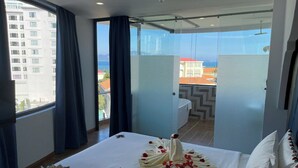 Ein Hotelzimmer mit einem großen Bett, Blick auf die Stadt und einem Balkon mit Tisch und Stühlen.