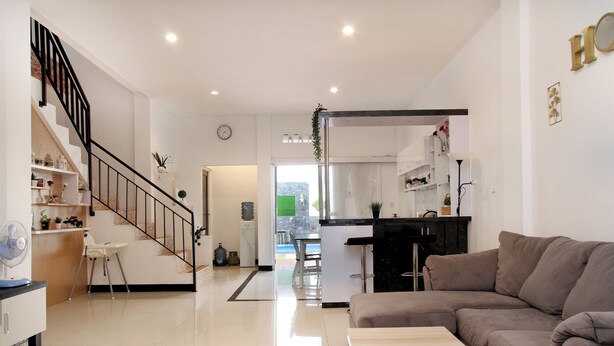 A modern living room with a staircase, a dining area, and a kitchen. - Villa Normandie (Cimahi)