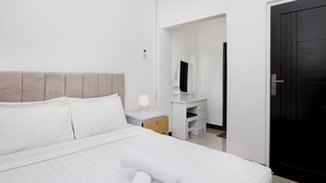 A hotel room with a bed, a nightstand, a dresser, a mirror, and a door. - Villa Normandie (Cimahi)