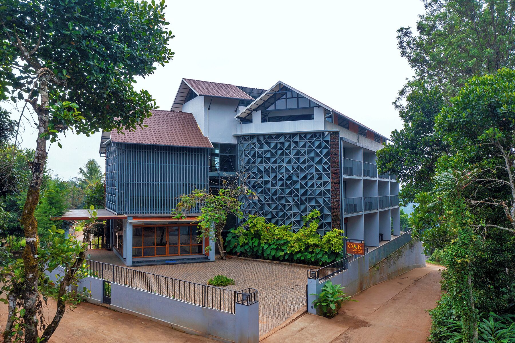 A modern building with a mix of glass and metal facade, surrounded by lush greenery.
