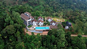 A residential area with multiple houses surrounded by dense forest. - Vbrings Oak Village (Devikolam)