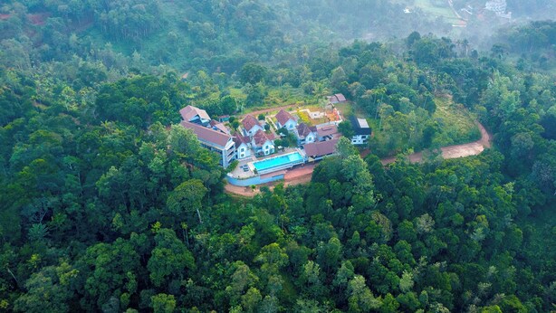 An aerial view of a resort with multiple buildings surrounded by dense forest. - Vbrings Oak Village (Devikolam)