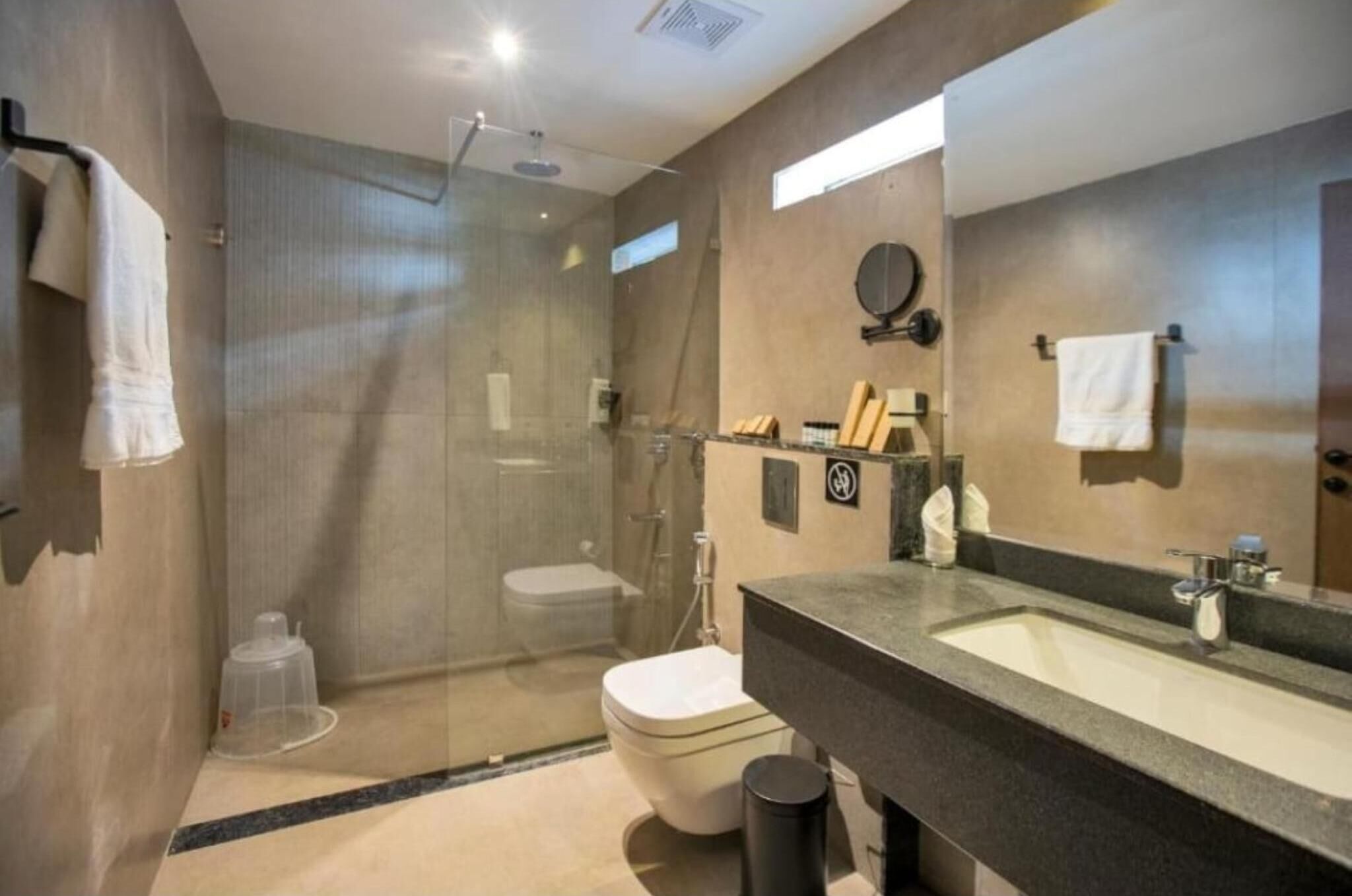 A modern bathroom with a glass-enclosed shower, a sink with a mirror, and a toilet.