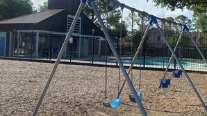 A playground with swings and a fenced area.