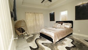 Une chambre à coucher avec un lit, une chaise, une fenêtre et un ventilateur de plafond.