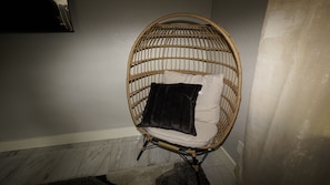 Relax in this cozy corner room with a comfortable wicker chair and plush cushion.