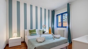 Un dormitorio con cama, mesita de noche y ventana con cortinas.