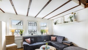 Una sala de estar moderna con un sofá modular, una mesa de centro redonda y una silla de mimbre.