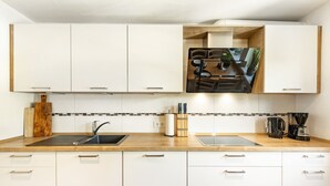 Una cocina moderna con armarios blancos, encimera de madera, un fregadero, una cafetera y un organizador de cuchillos.