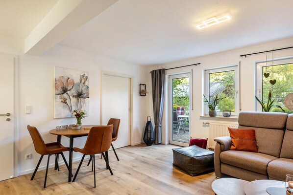 A modern living room with a dining area, large windows, and a view of the outdoors.