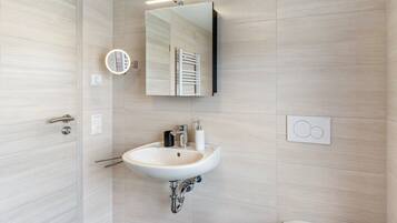 Ein modernes Badezimmer mit Waschbecken, Spiegel, Handtuchhalter und Toilette.