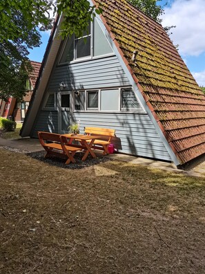 Una casa moderna con techo inclinado, un banco de madera y una planta en maceta.
