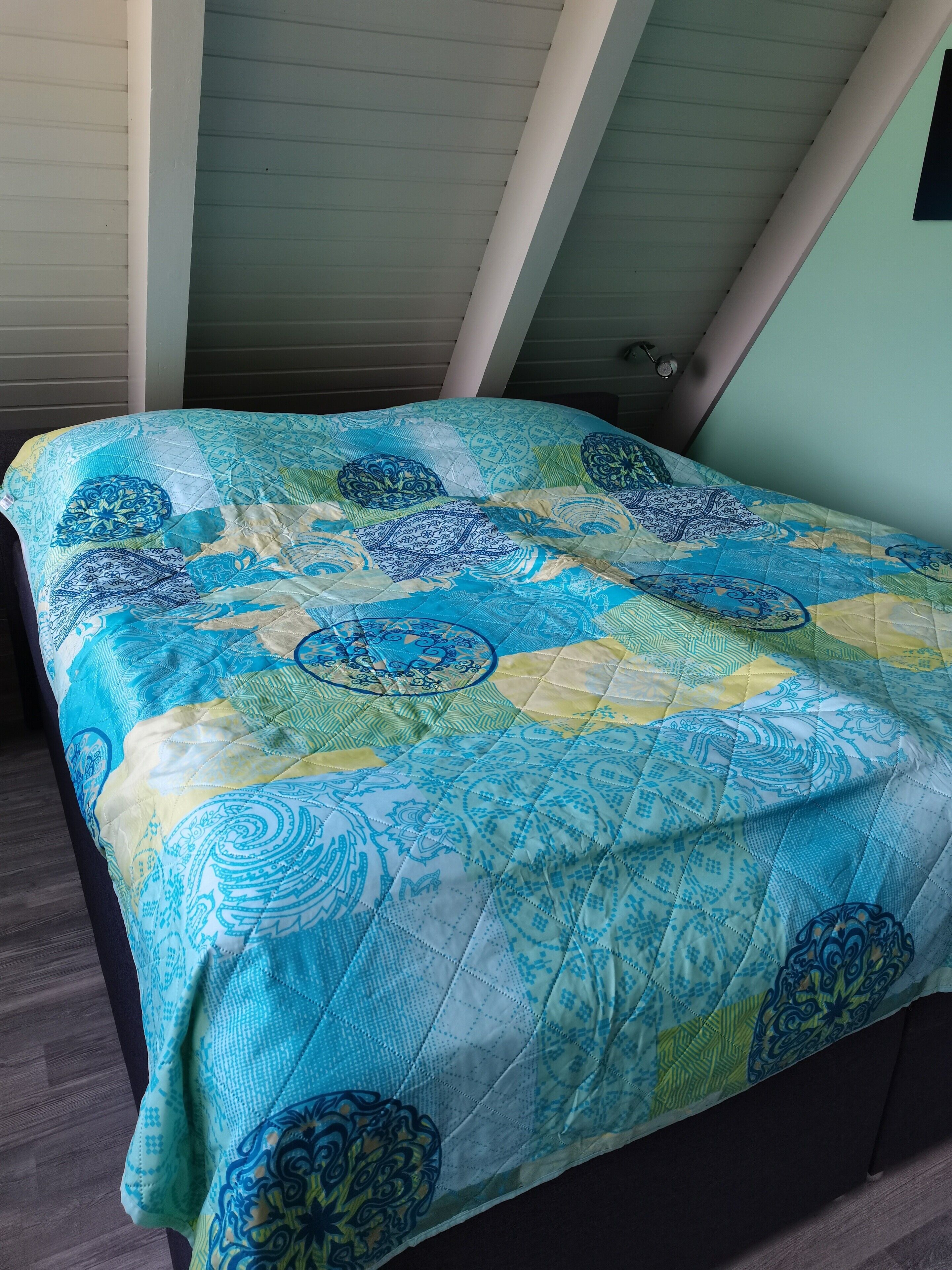 Un lit recouvert d’une couette bleue et jaune.