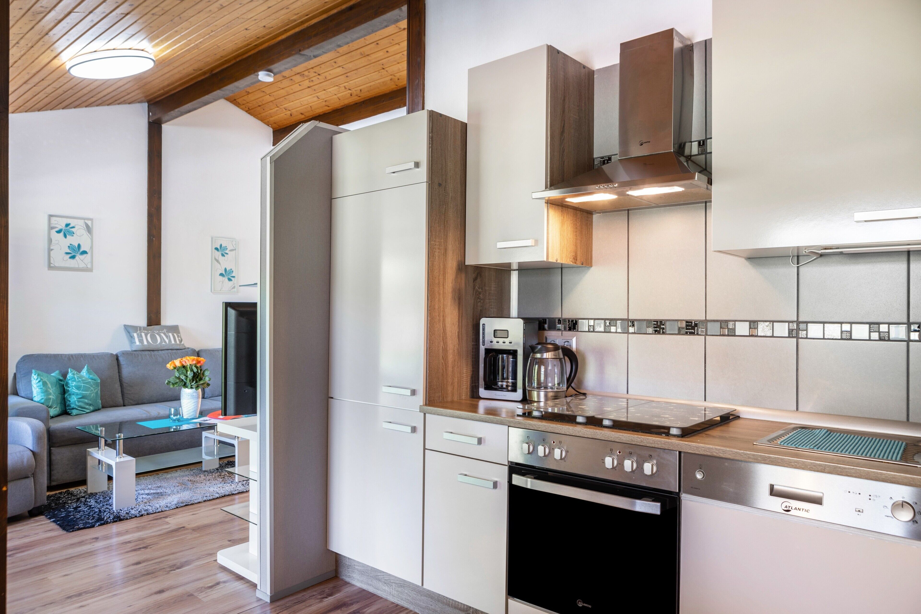 Une cuisine moderne dotée d’appareils électroménagers en acier inoxydable, de meubles en bois et d’une table basse en verre.
