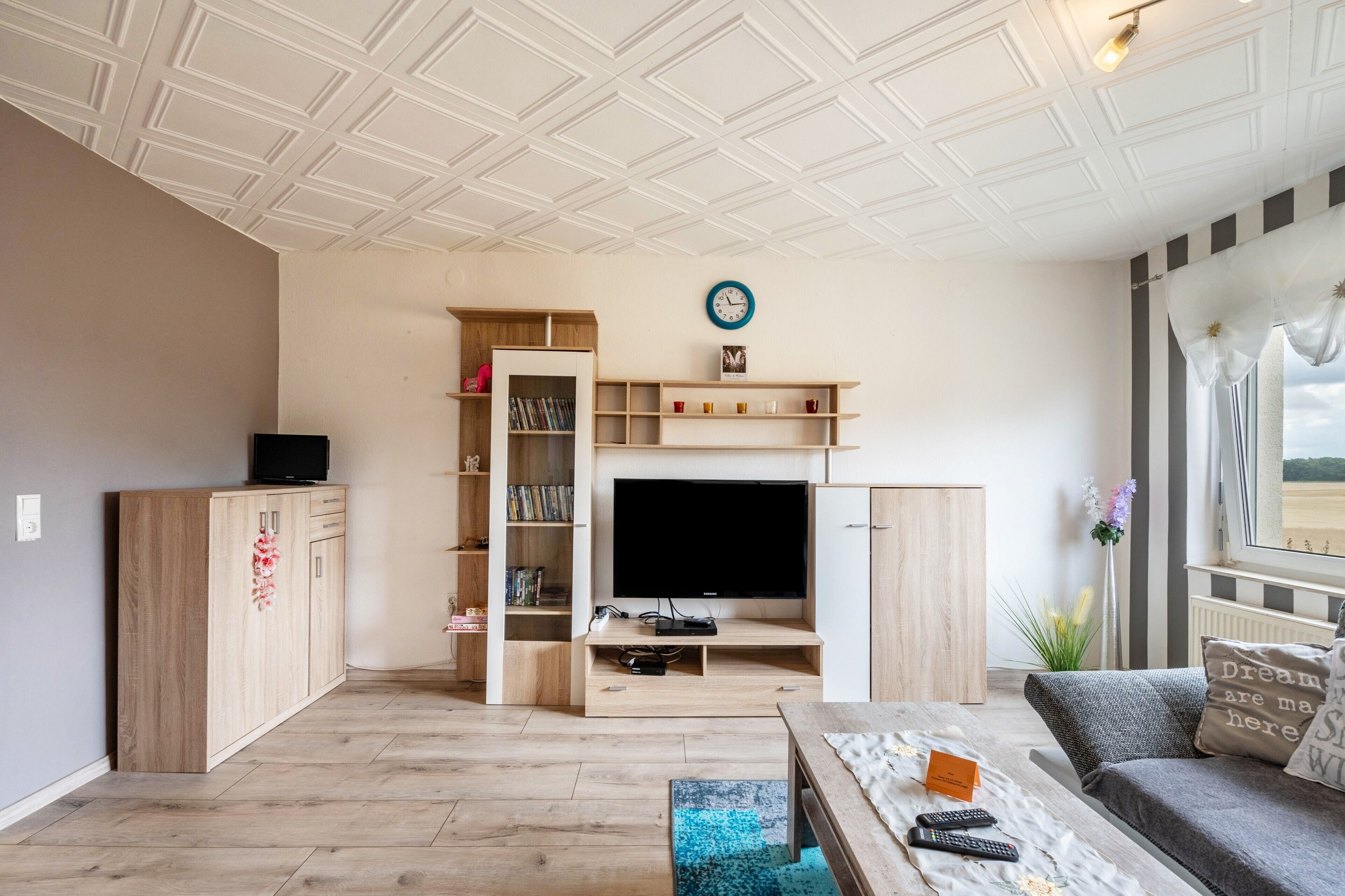 Una sala de estar con televisor, muebles de madera, una estantería y un sofá.