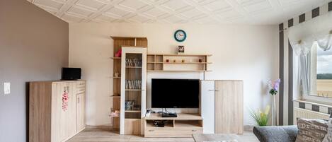 A living room with a TV, wooden cabinets, a bookshelf, and a sofa.