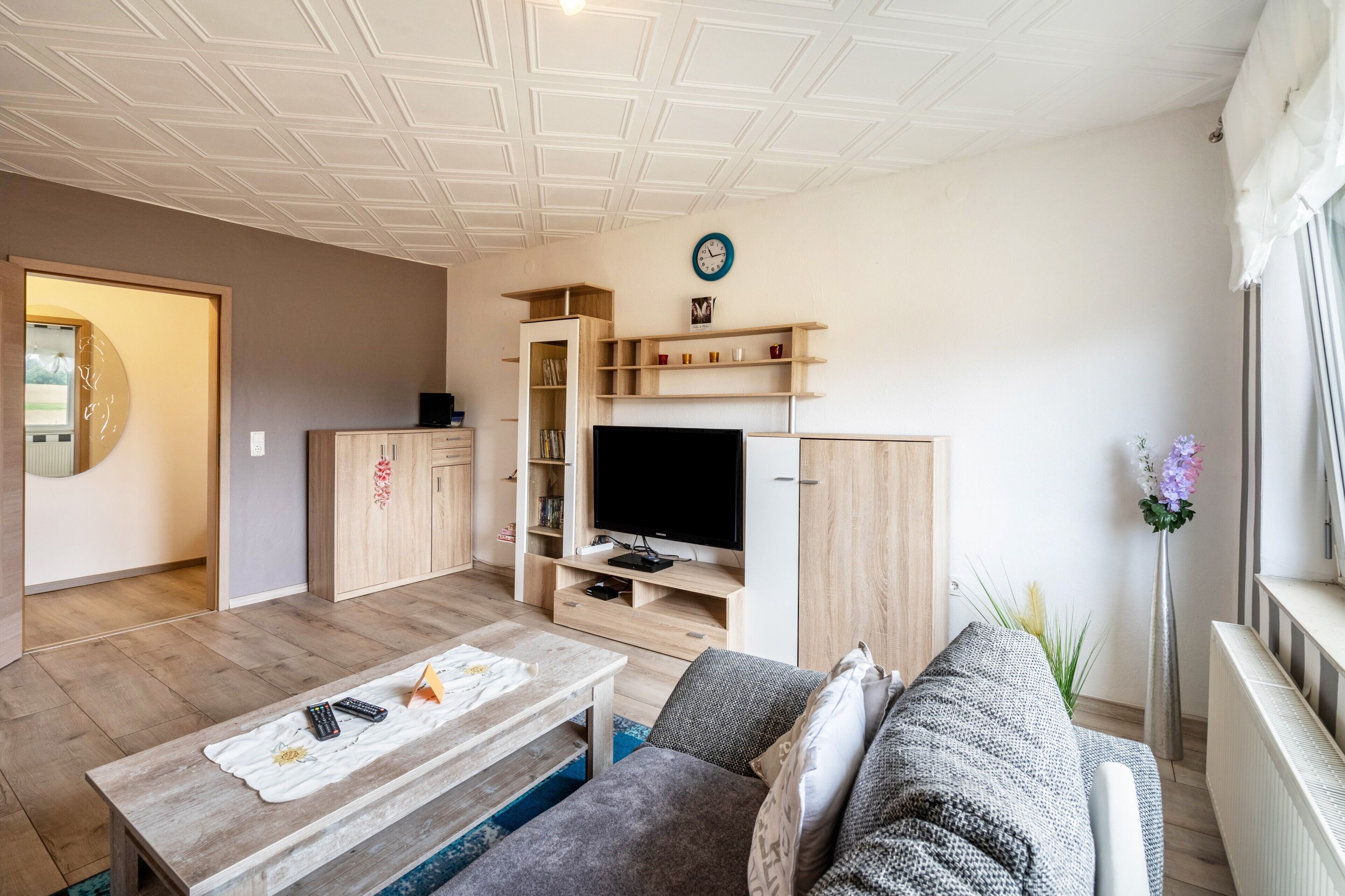 A modern living room with a television, wooden cabinets, a sofa, and a coffee table.