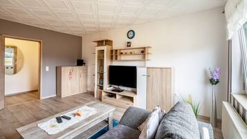 A modern living room with a television, wooden cabinets, a sofa, and a coffee table.