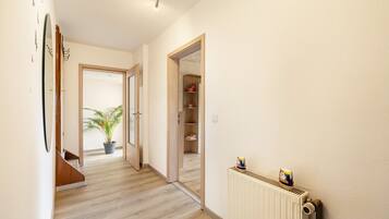 A hallway with a radiator, a potted plant, and a door leading to a room.